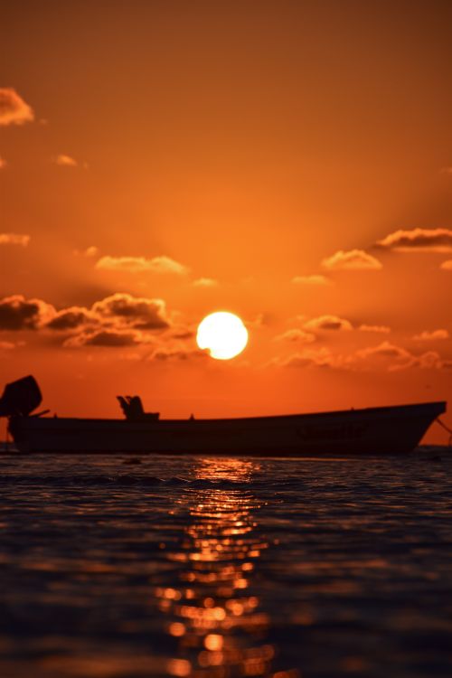 Free Silhouette of a boat against a vibrant Mexican sunset over calm waters. Stock Photo