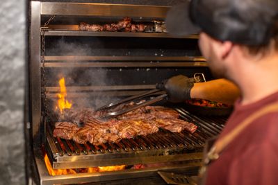 A cook turning steaks over an open flame grill — photo by Vidal Balielo Jr. on Pexels
