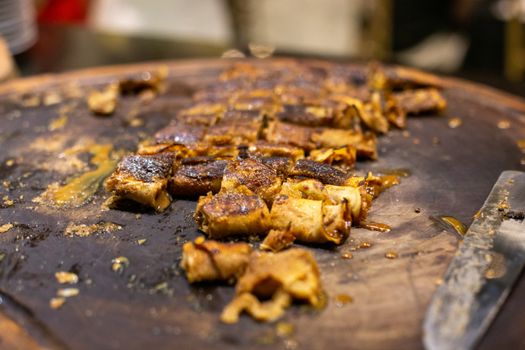 A close-up view of sliced roasted meat pieces on a cooking tray, showcasing a deliciously crispy texture.