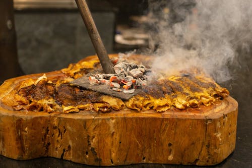 Free A Yellow Wrapped Food Toasting Under a Steel Plate with Charcoal Stock Photo