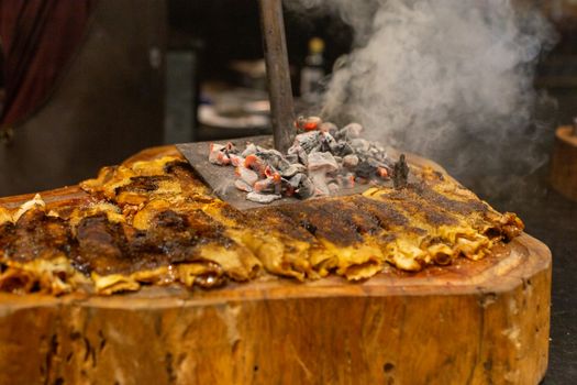Close-up of grilled meat sizzling under hot embers with smoky aroma.