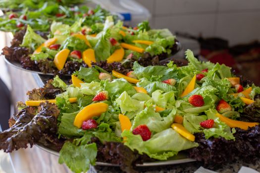 Close-up of fresh mixed fruit and lettuce salad platter with vibrant strawberries and mango slices.