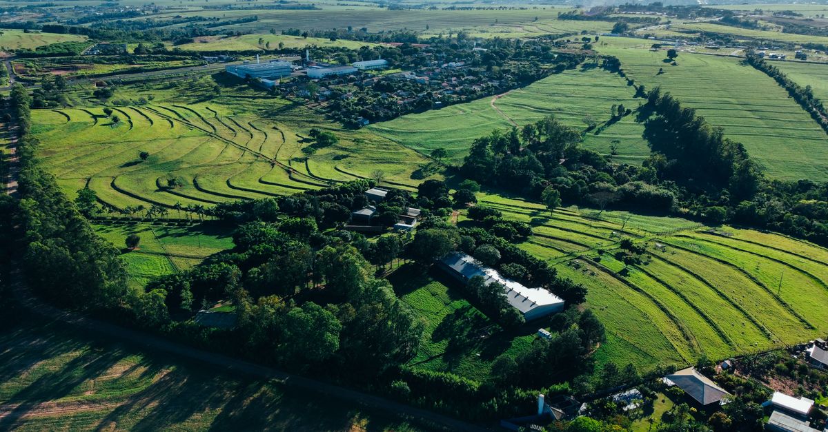 Aerial view of a suburban housing development encroaching on a small family farm with a contrasting green field