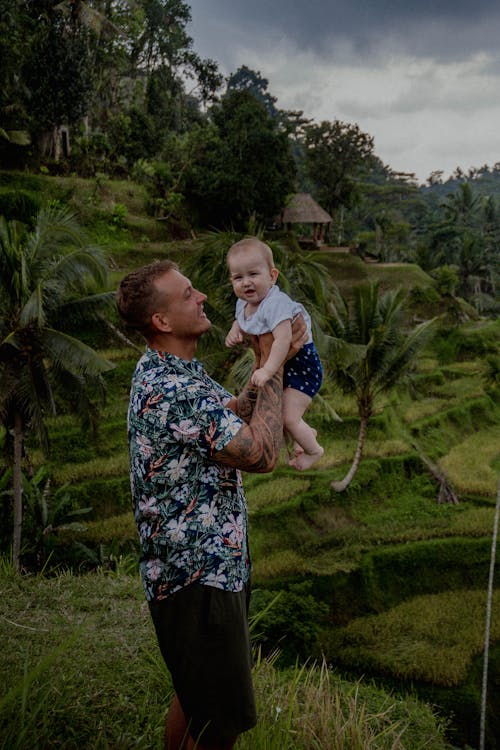 Man Carrying a Baby on Green Grass Field