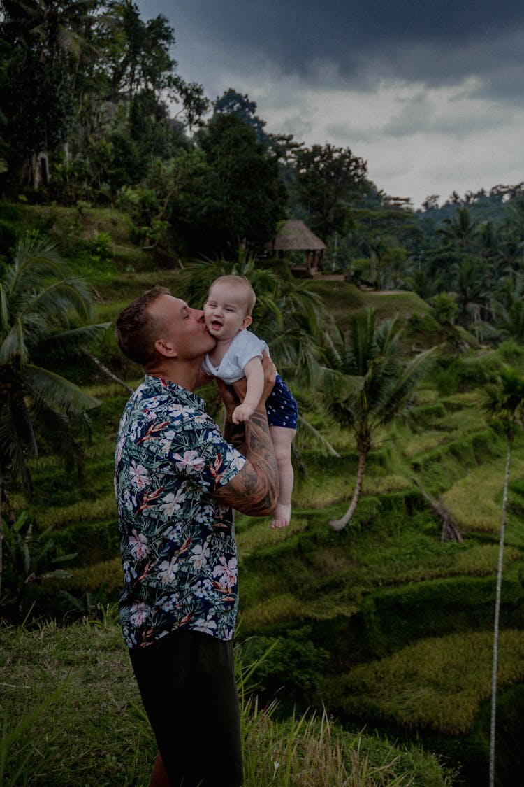 Man Kissing A Baby On Green Grass Field