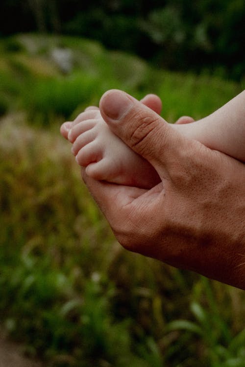 Hand of an Adult Holding a Foot of a Baby