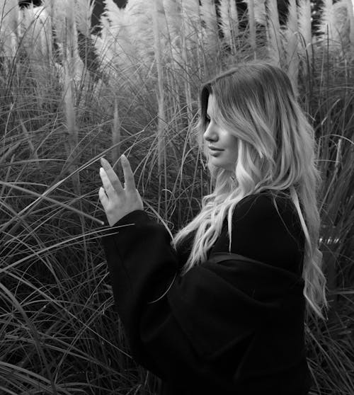 Grayscale Photo of a Woman near Tall Grass