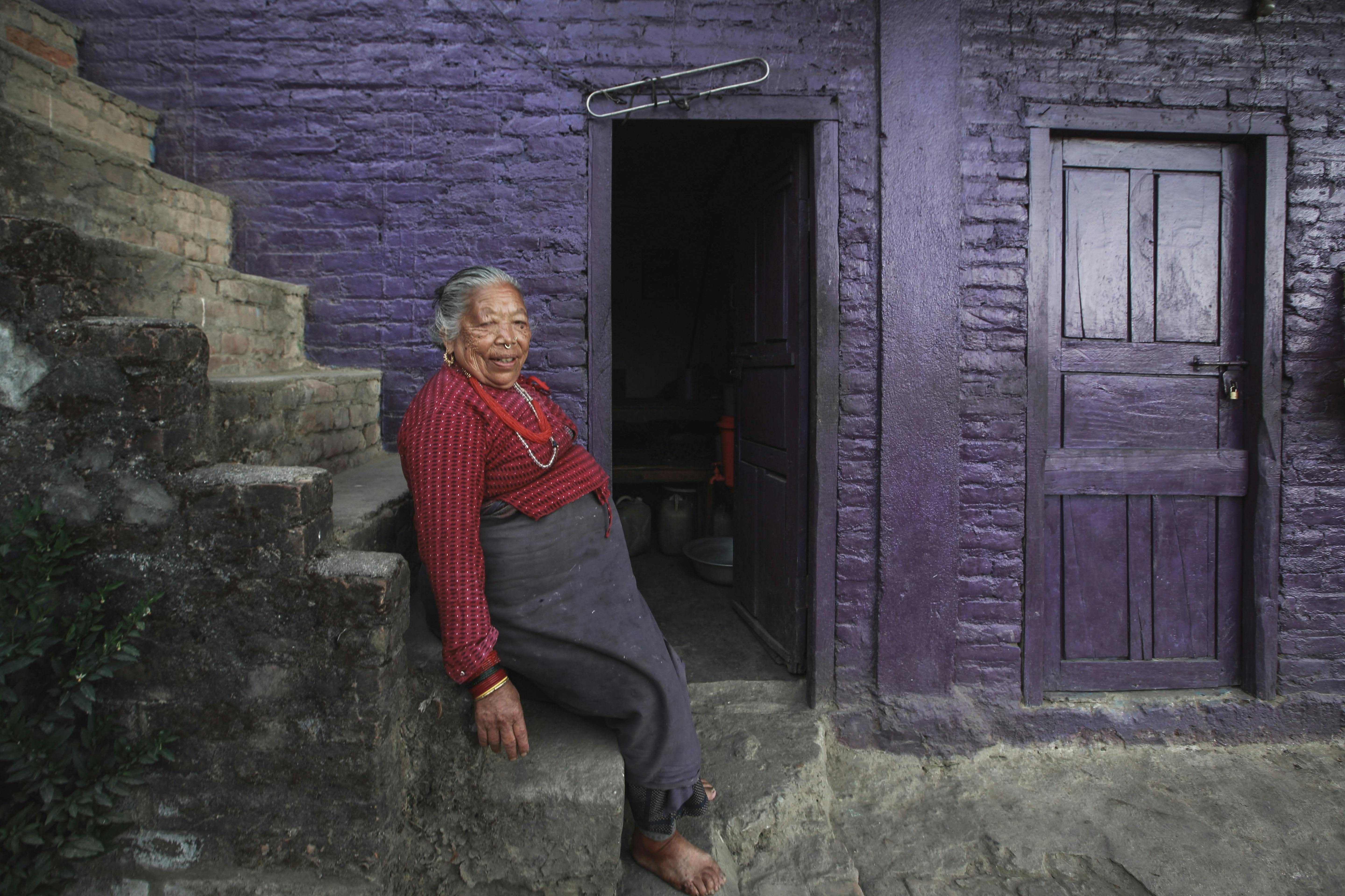 retiree sitting in front her house