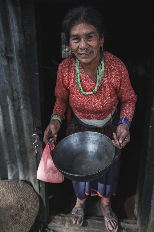 Photo of a Woman Smiling while Holding a Pot