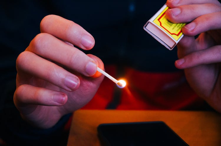 Person Holding Lighted Match Stick