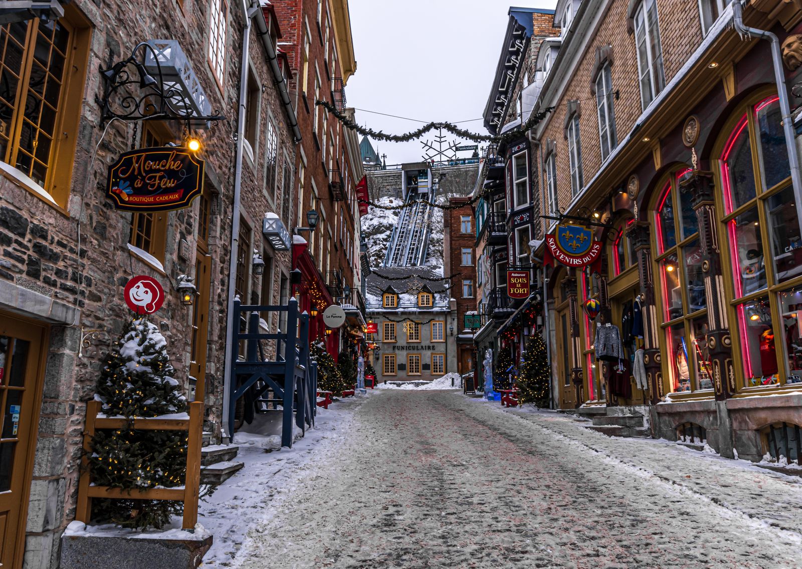 Rue du Petit-Champlain in Québec City's Lower Town in winter, with Christmas trees, garlands and the funicular at the end of the street