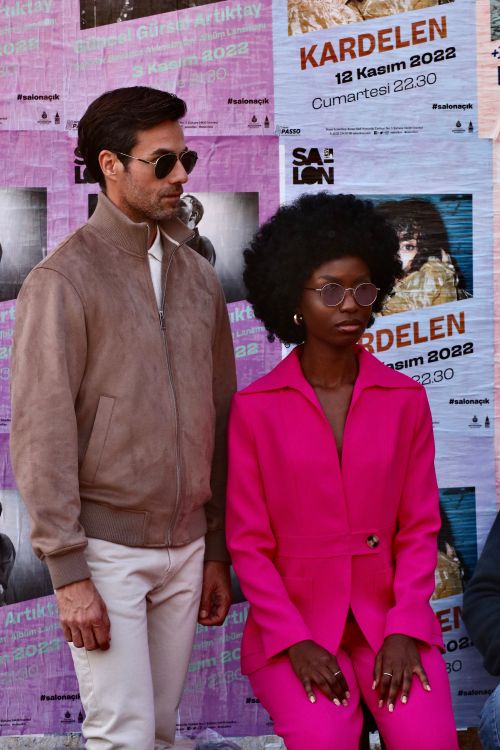 Free Fashion-forward pair posing with bold urban posters, capturing city chic. Stock Photo