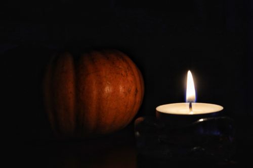 Free A candle illuminates a pumpkin in a dark, warm autumn setting. Stock Photo