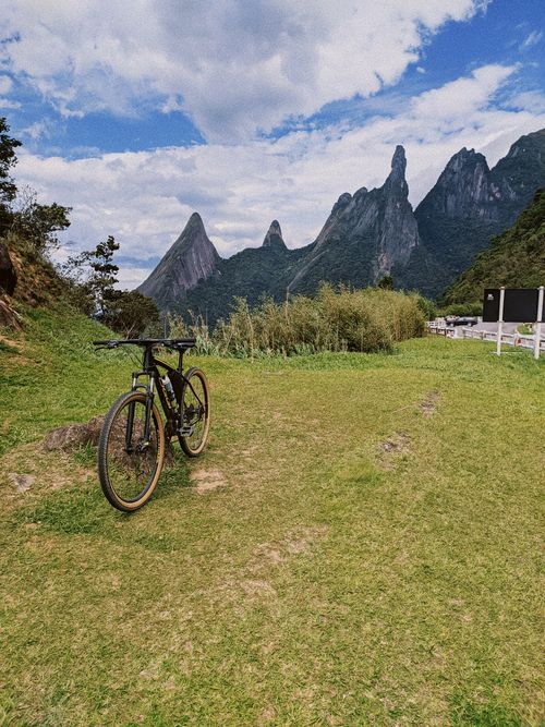 Free Mountain bike on a grassy field with stunning mountain views under a cloudy sky, perfect for adventure enthusiasts. Stock Photo