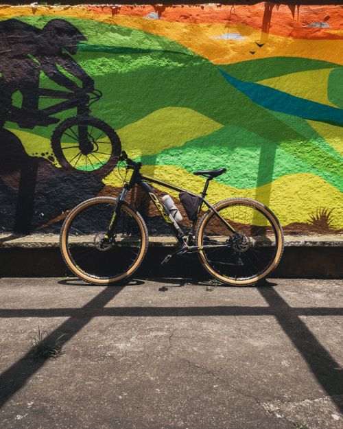 Free A bicycle parked against a vibrant graffiti wall under sunlight, creating an urban artistic scene. Stock Photo