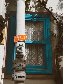 Turquoise window on a house with Cunda signs, capturing a vintage street scene.