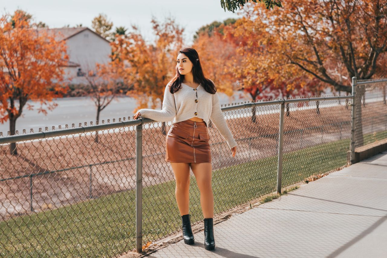 Woman in a white cardigan and brown suede-look mini skirt with black ankle boots