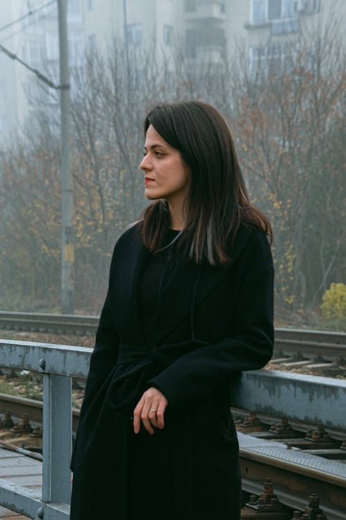 A Woman in a Black Coat Leaning on a Railing