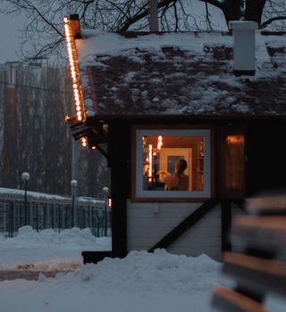 A warm glimpse inside a snowy cabin with glowing string lights on a winter evening.