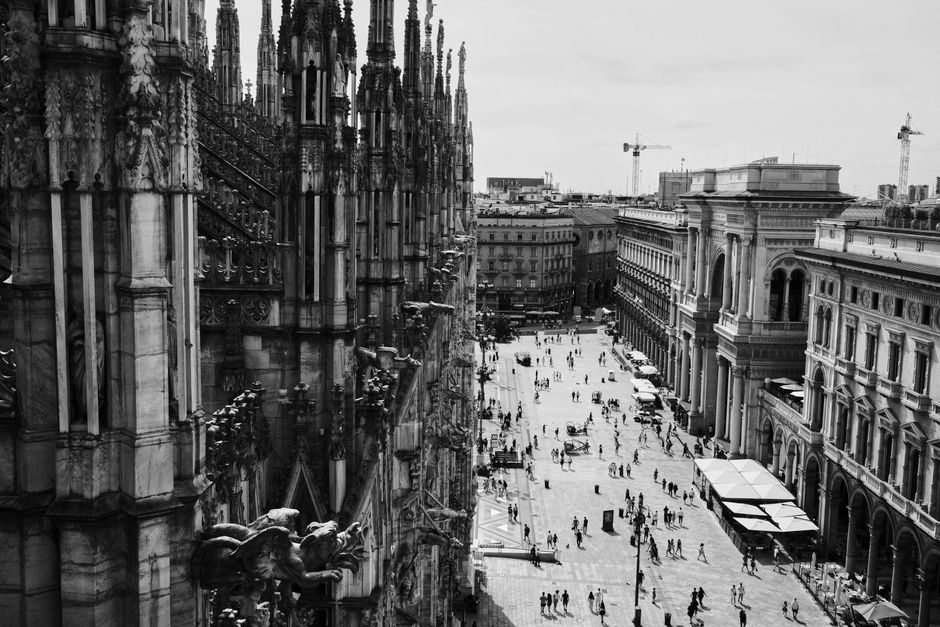 Black and white aerial view of Milan's iconic Gothic architecture and bustling streets.