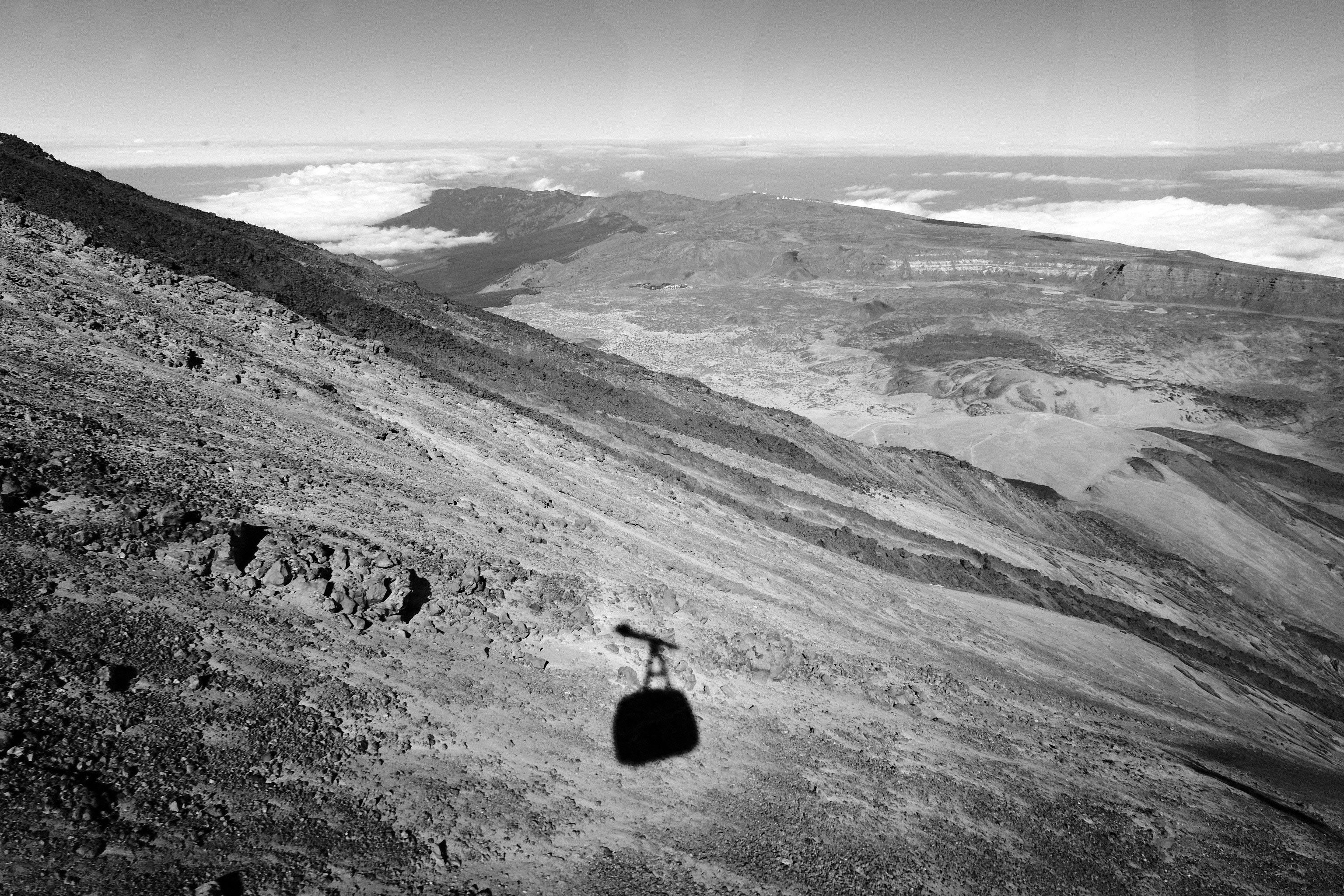 Grayscale view of Mount Teide with cable car shadow and rocky terrain in Spain.