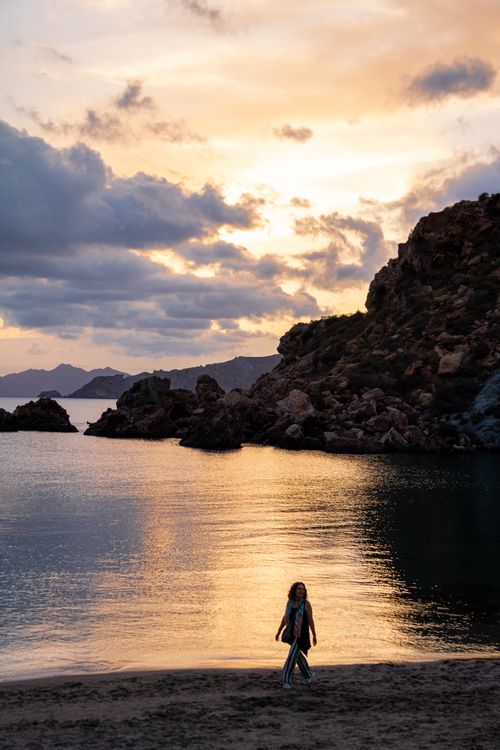 Free Silhouette of woman walking by the sea during a stunning sunset in Cartagena, Spain. Stock Photo