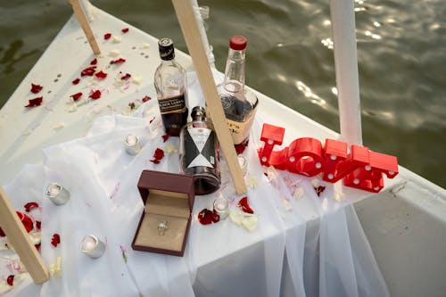 An Engagement Ring beside Bottles of Alcoholic Beverages