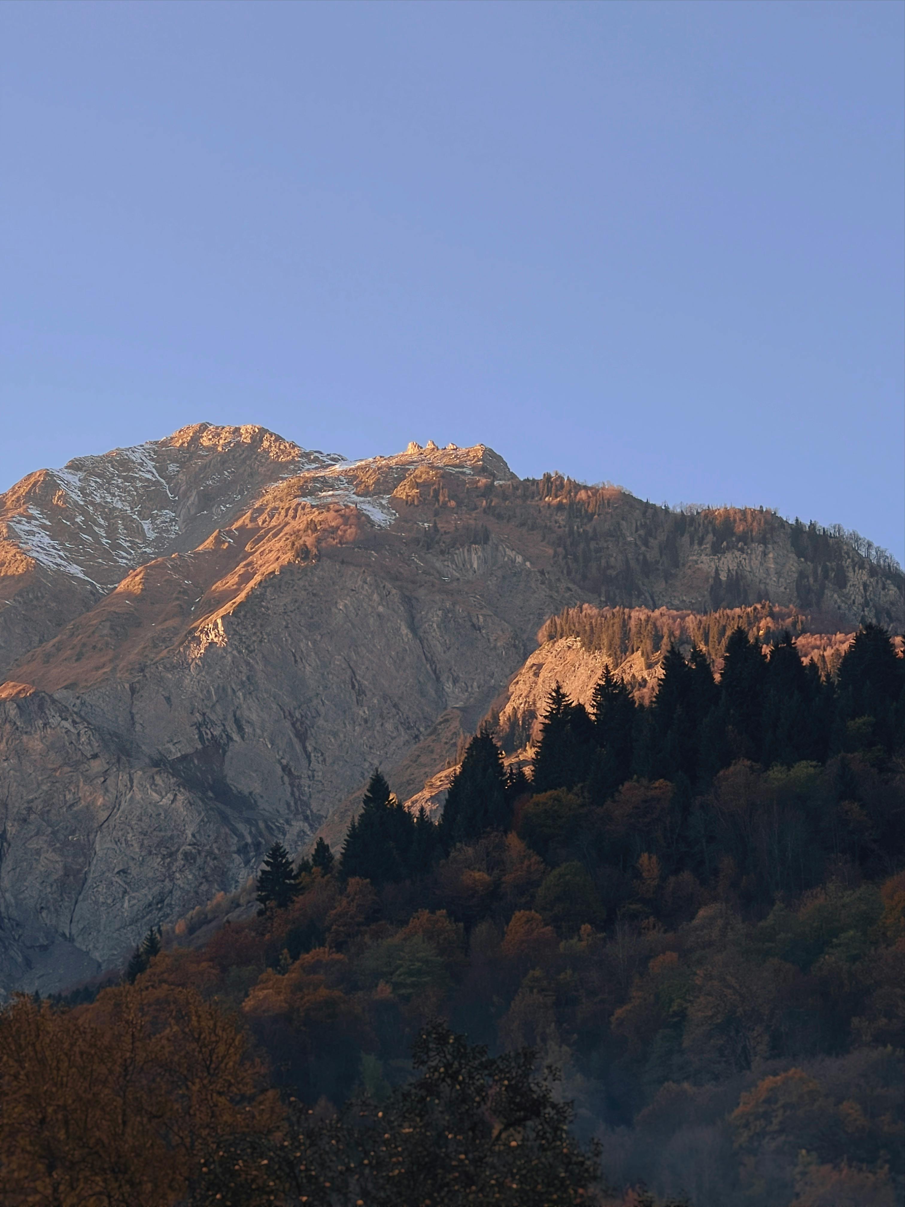 Capture the serene beauty of a mountain range bathed in the warm glow of sunrise.