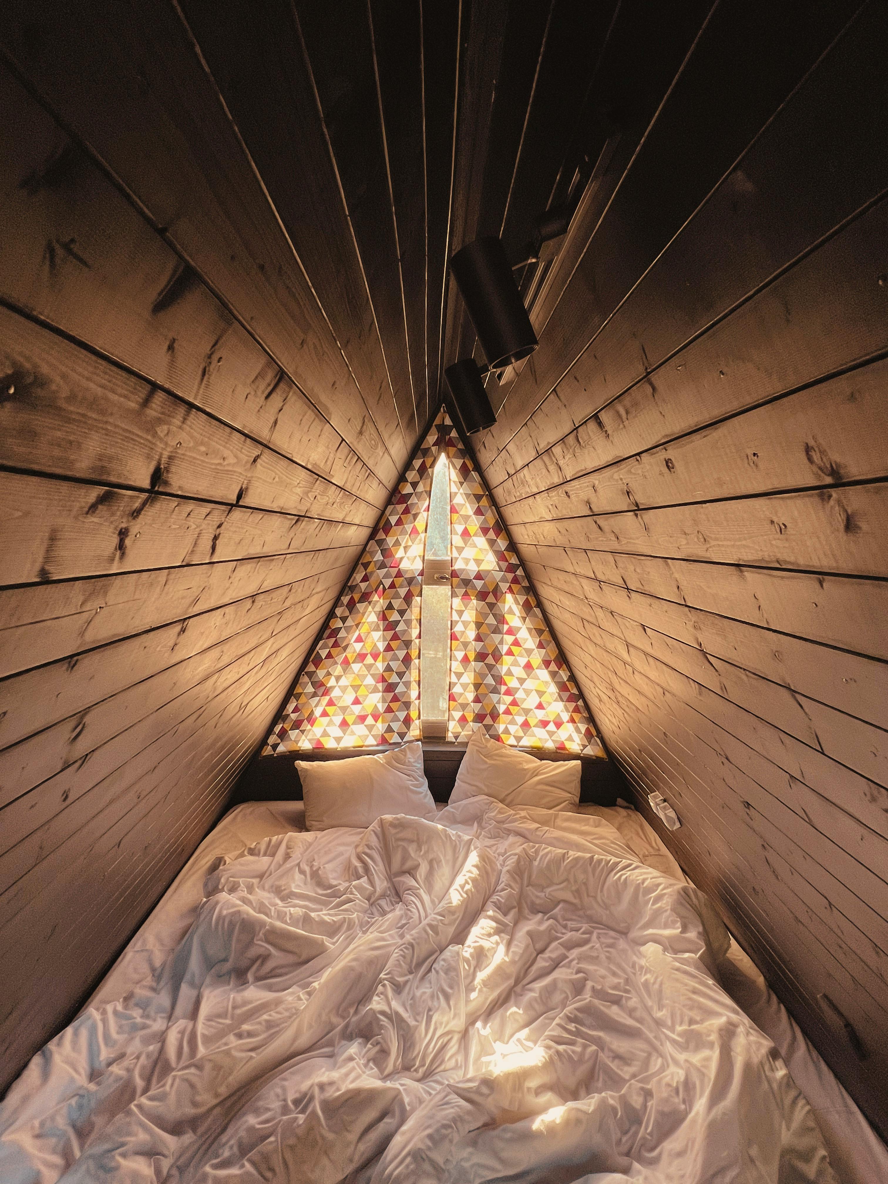 Warm and inviting interior of an A-frame hut with comfortable bedding, in Georgia.