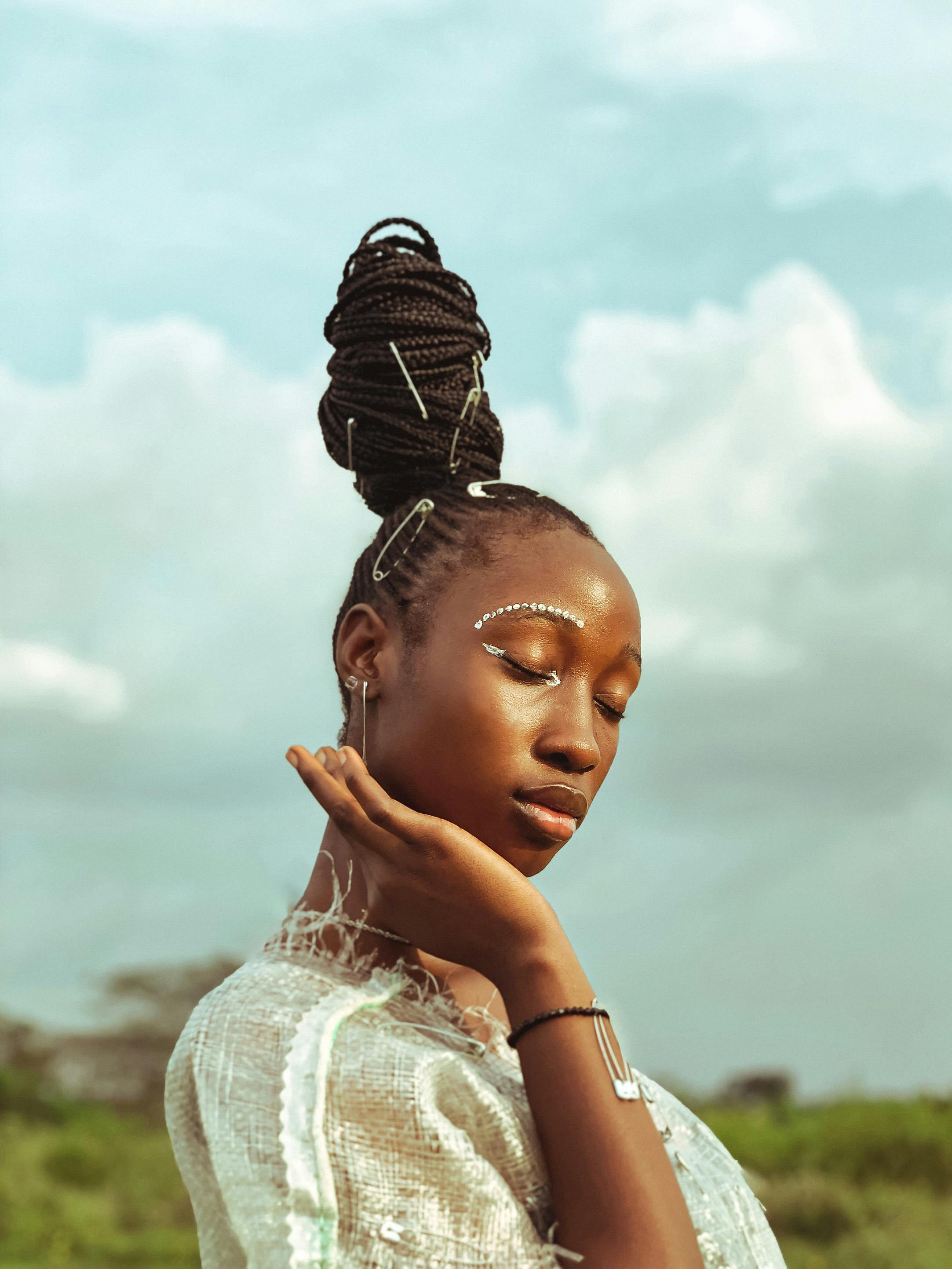 Elegant portrait of an African woman with eyes closed and braided updo, outdoors in Nigeria.
