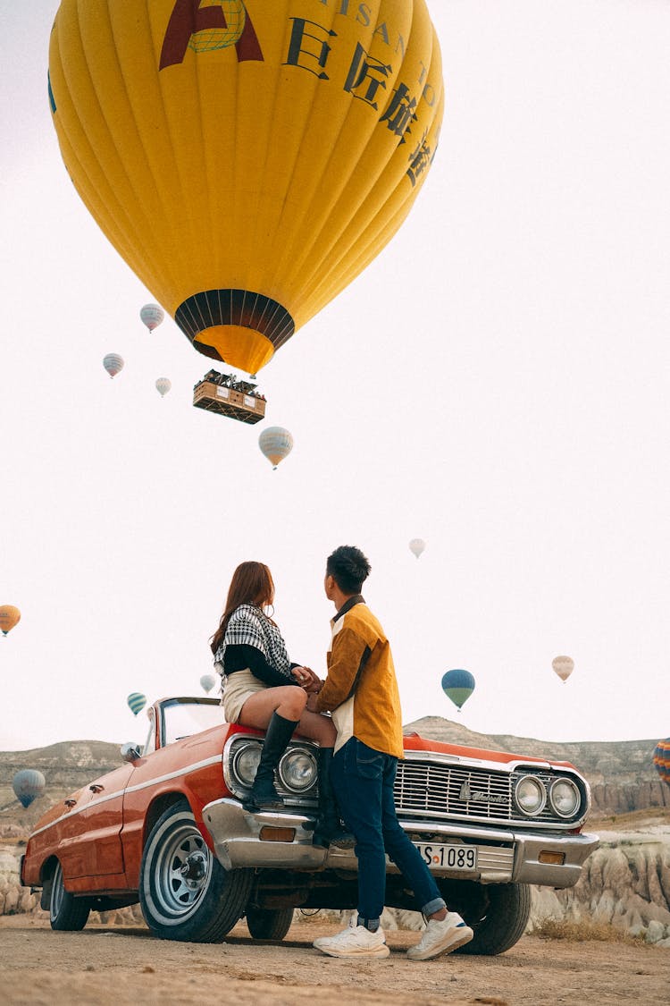 Couple With Convertible Car Under Balloons On Sky