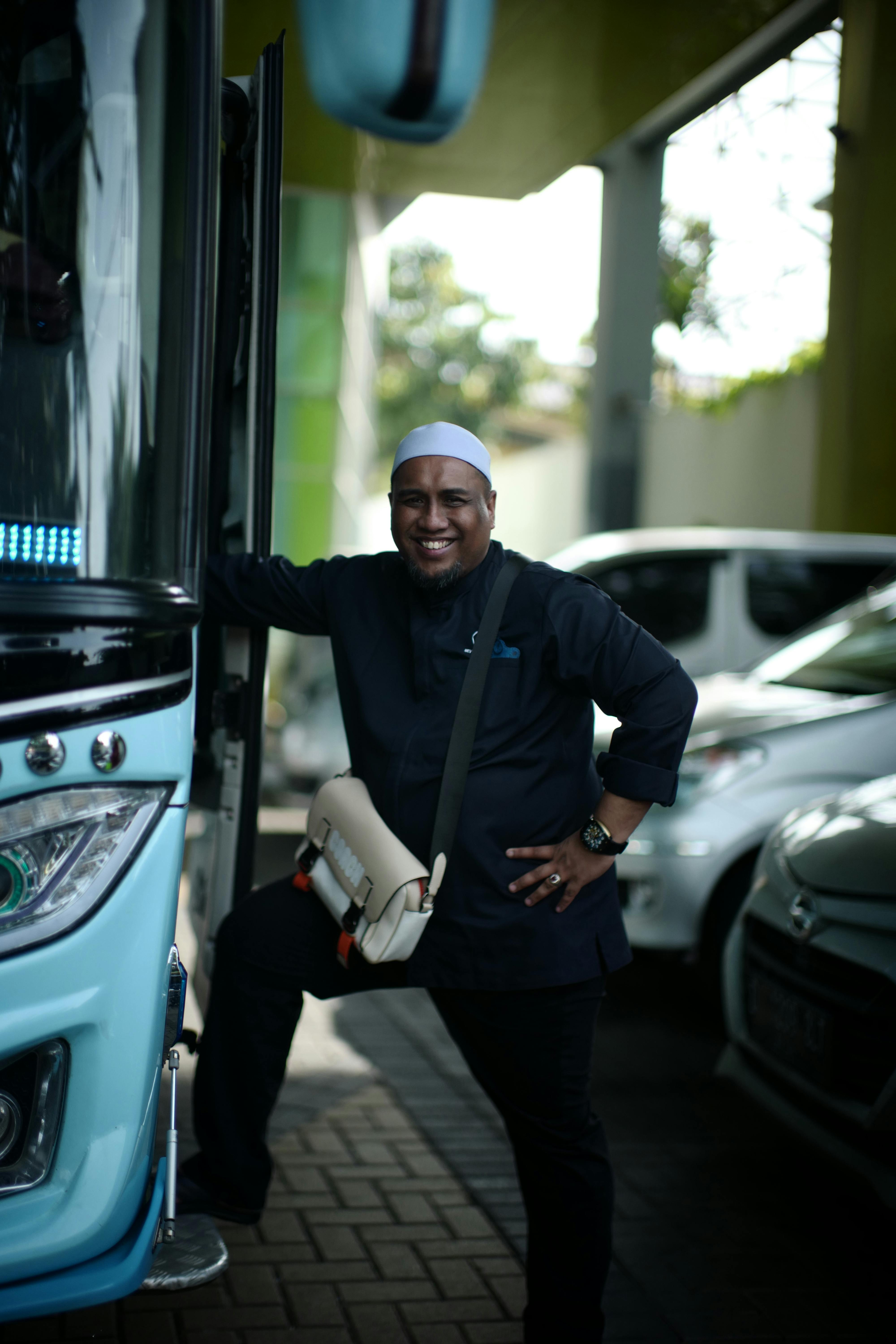 Free Cheerful bus driver posing at Jakarta terminal, showcasing his profession with a bright smile. Stock Photo