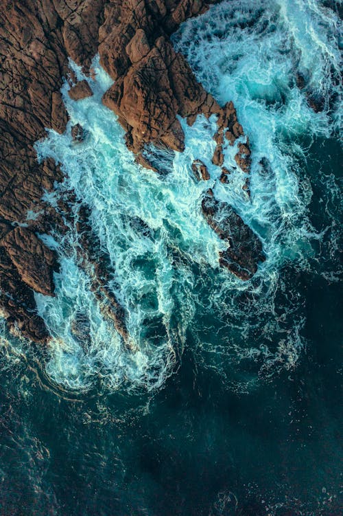 An Aerial Shot of Waves Crashing on a Rocky Shore