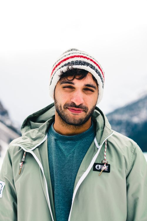 Free A man in a beanie and jacket stands at snowy Lake Louise, Canada. Stock Photo