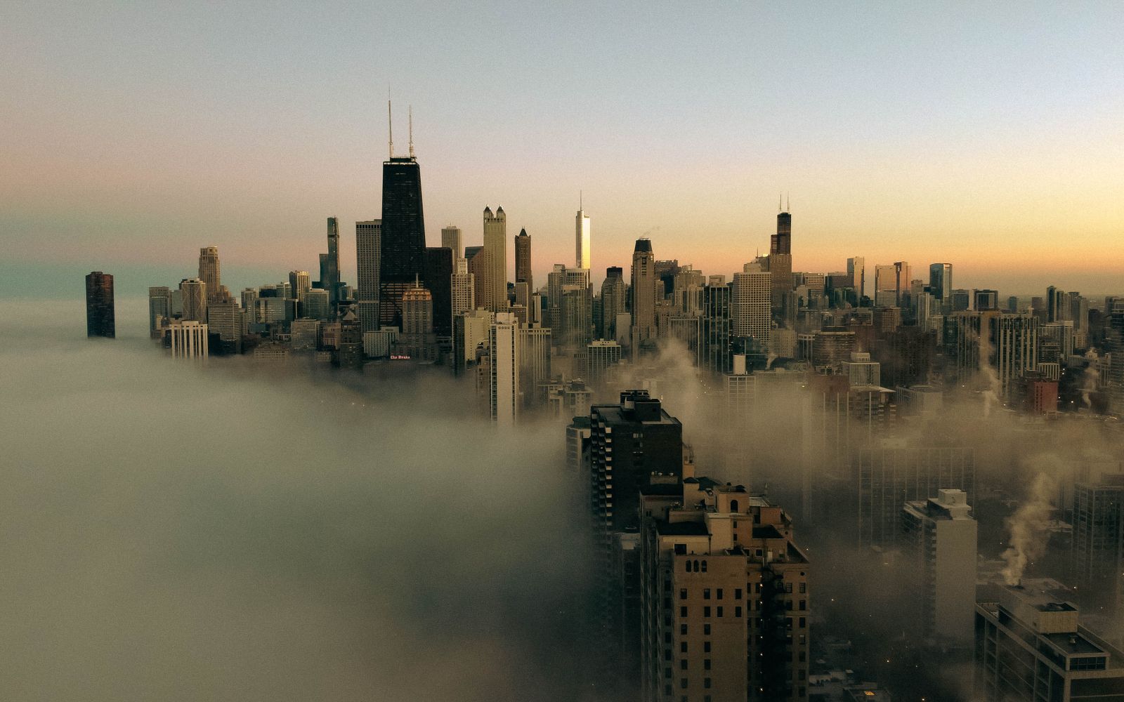 Aerial view of Chicago's skyline shrouded in fog at sunset.