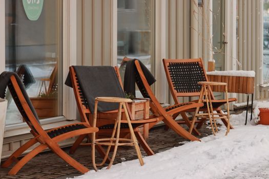 Charming outdoor cafe with wooden chairs on a snowy sidewalk, perfect for a winter scene.