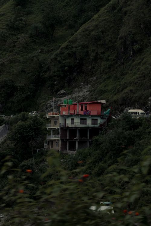 Free A colorful multi-story house nestled on a lush mountainside, surrounded by greenery. Stock Photo