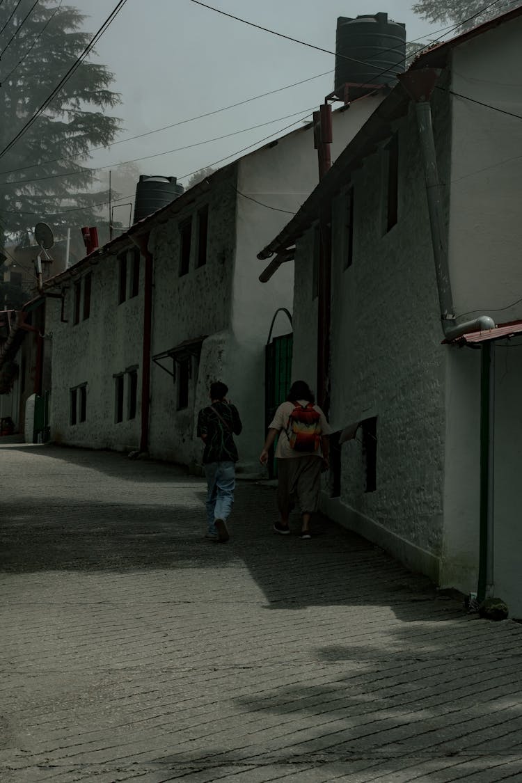 People Walking On The Street Near Concrete Houses