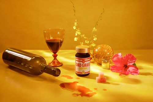 Free Aesthetic composition with wine, flower, and supplement bottle on a yellow background. Stock Photo