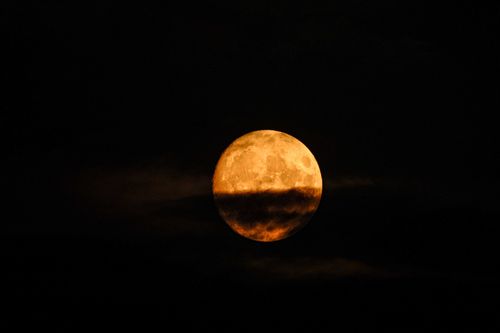 Free A captivating view of the full moon partially shrouded by clouds against a dark night sky. Stock Photo