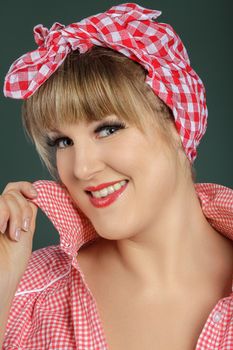 Portrait of a smiling woman in a red checkered headscarf and shirt, exuding warmth and charm.