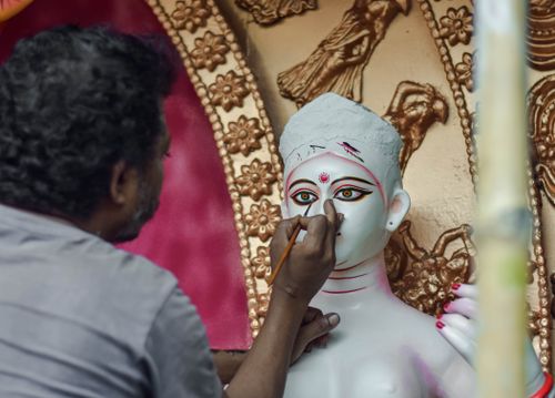 Free An artisan in Kolkata paints intricate details on a Hindu goddess idol, showcasing cultural craftsmanship. Stock Photo