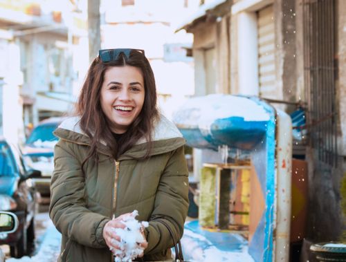 Free Joyful young woman holding a snowball on a winter day in Durrës, Albania. Stock Photo