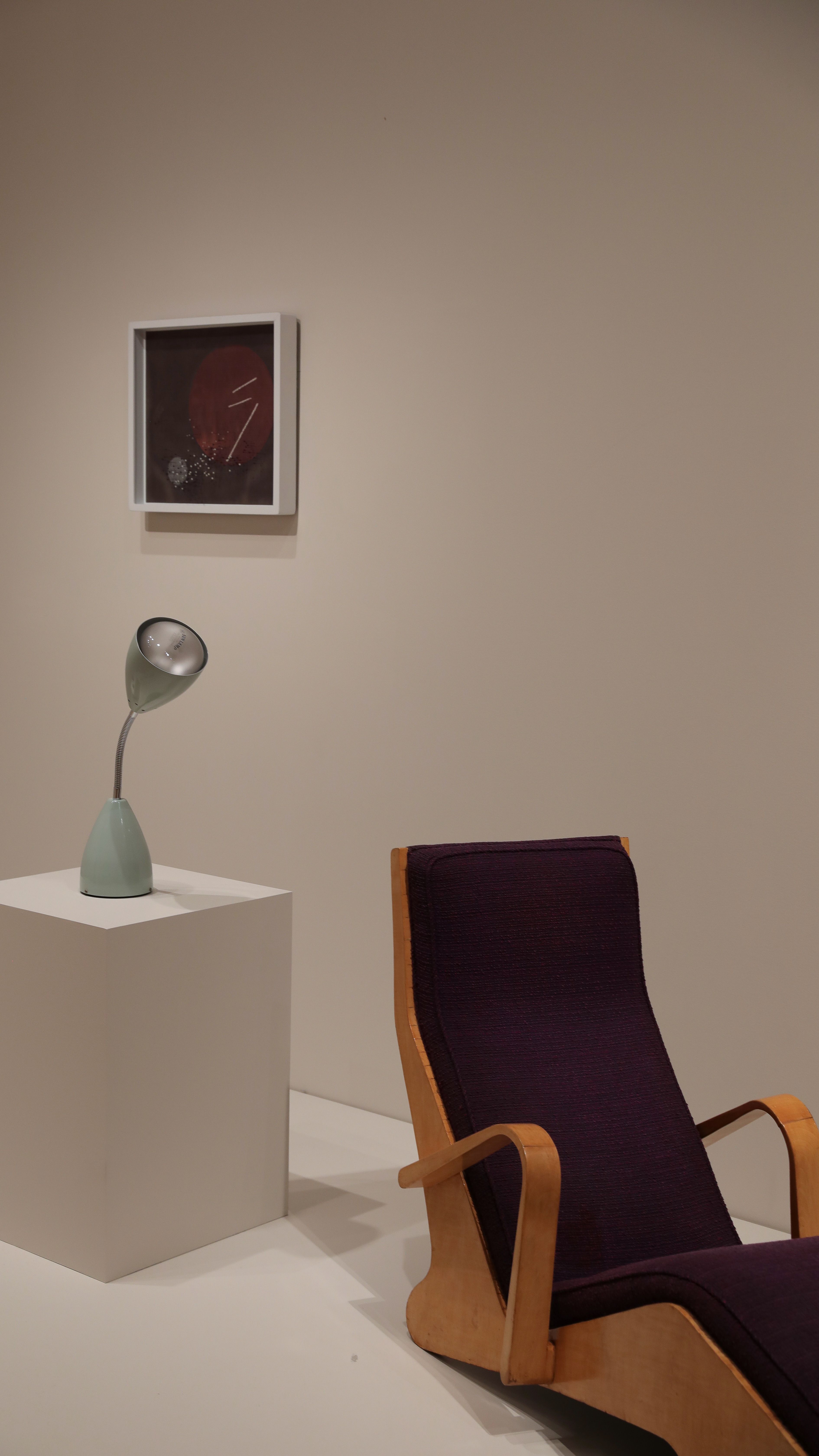 Stylish interior featuring a purple armchair, modern lamp, and abstract art piece.