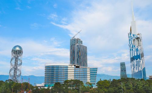 Free Vibrant urban skyline featuring modern skyscrapers and unique architectural towers against a blue sky. Stock Photo