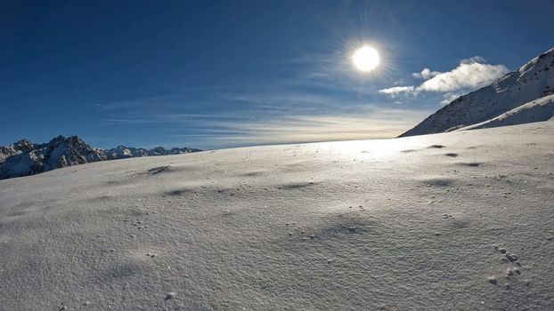 Stunning winter scene of snow-covered Alps under a bright sun, perfect for scenic and travel themes.