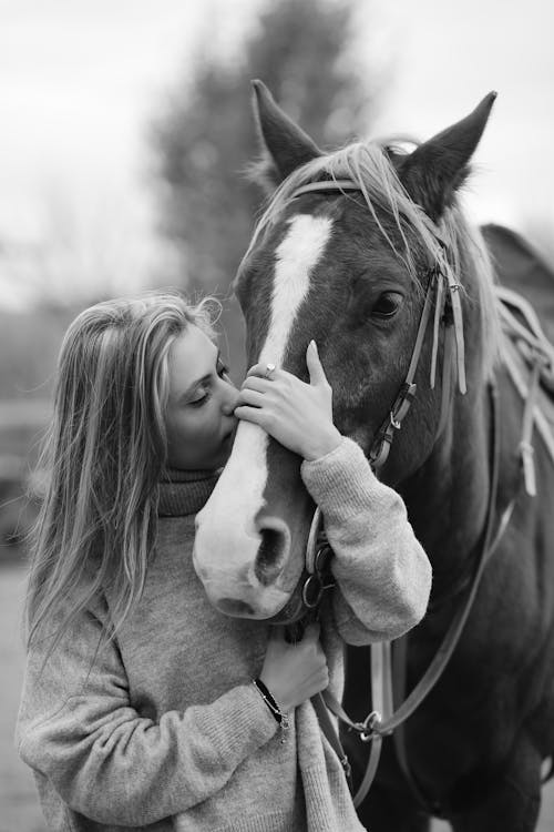 Black and White Photograph of a Woman Kissing a Horse
