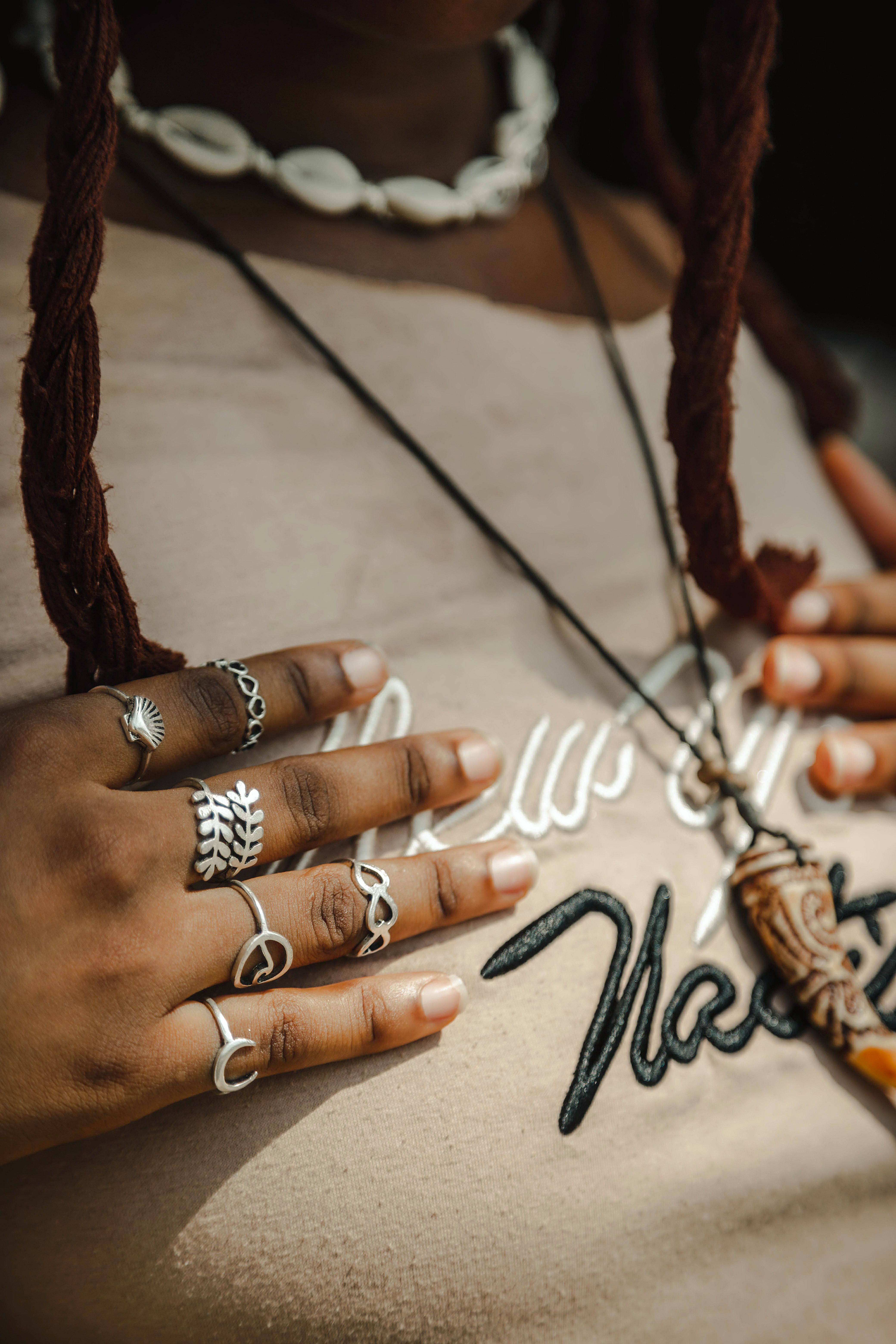 A stylish close-up of a woman's hands adorned with rings and a shell necklace.