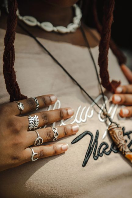 A stylish close-up of a woman's hands adorned with rings and a shell necklace.