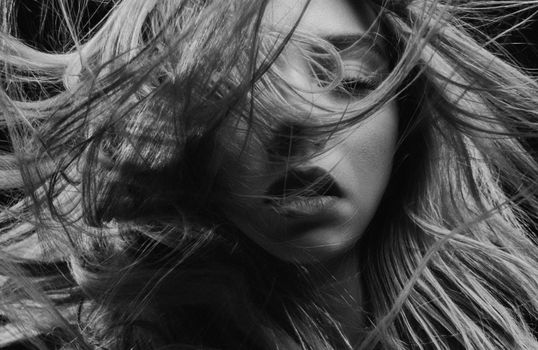 Dramatic black and white portrait of a woman with dynamic hair movement.